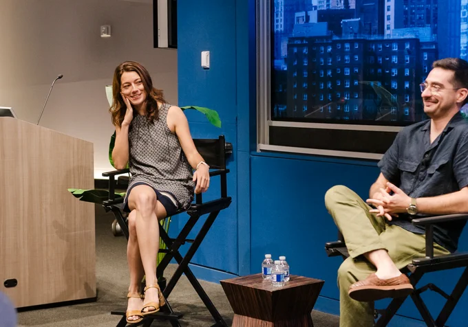 Two people engaged in a discussion sit at the front of an auditorium