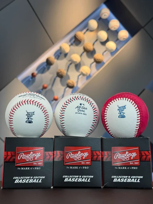 Three baseballs resting on their boxes.
Pictured left: A baseball with a Home Run Derby logo.
Pictured center: A baseball with blue and red seams and an All-Star Game logo.
Pictured right: A “Money Ball” baseball that is half red and has a Home Run Derby logo.