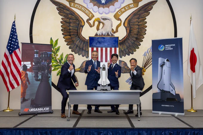 Ursa Major and I Space Carrier representatives pose excitedly behind model of a rocket.