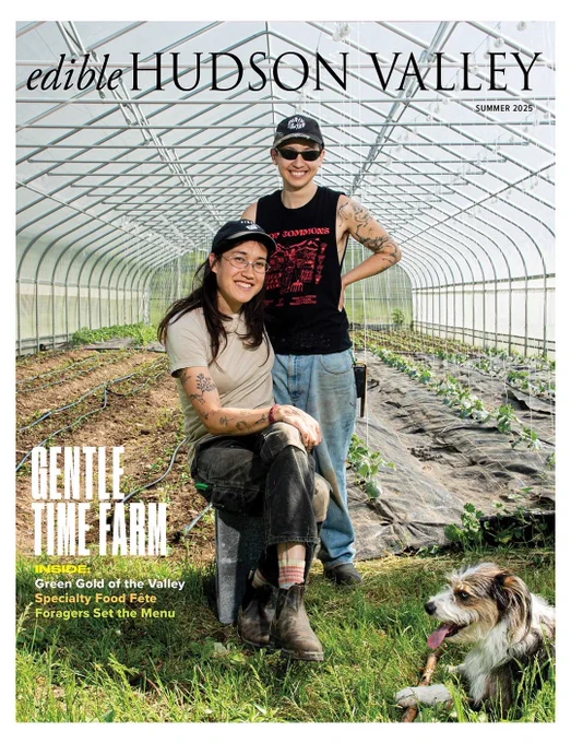 A magazine cover for "edible Hudson Valley" with two people and dog posing inside a hoophouse