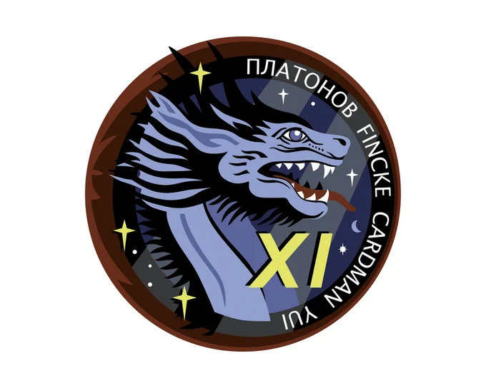 The Crew-11 mission patch symbolizes teamwork, exploration, and deep connections across nations, agencies, and families. The colors white, red, and blue honor the flags of the crew's nations, while three gold stars represent the unity of their space agencies. Two sunbeams forming the number "11" illuminate a blue circle, nodding to Voyager’s Pale Blue Dot image and our shared home. The dragon's eye reflects Earth, emphasizing exploration and perspective from space. The dragon, reminiscent of family crests, stands as a mission guardian. Stars honor the crew's children, inspiring future generations. A red flame encircles the patch, symbolizing launch power, reentry plasma, and the full journey—departure, work aboard the ISS, and safe return. Crew-11: Together, we rise.
