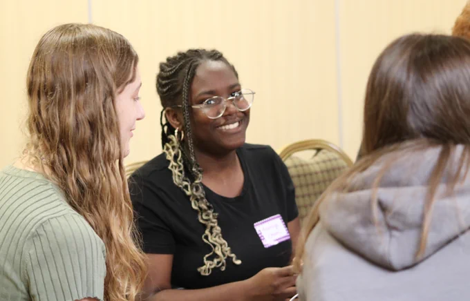 a young woman smiling at the camera in a group of people 