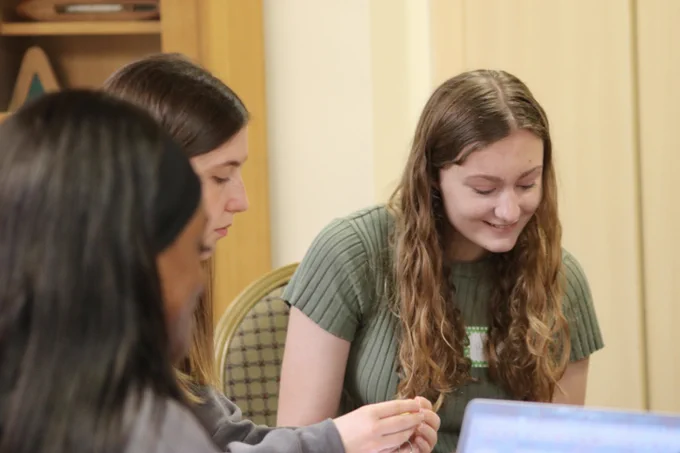 a young woman smiling looking down at a laptop