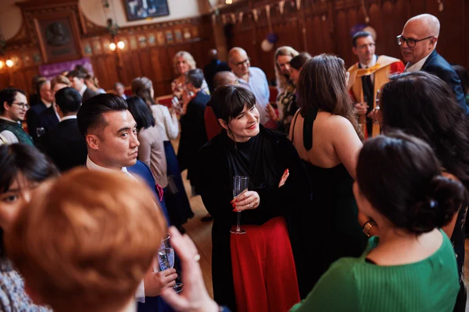 Colour photo of guests stood in the Rainy Hall talking to one another.