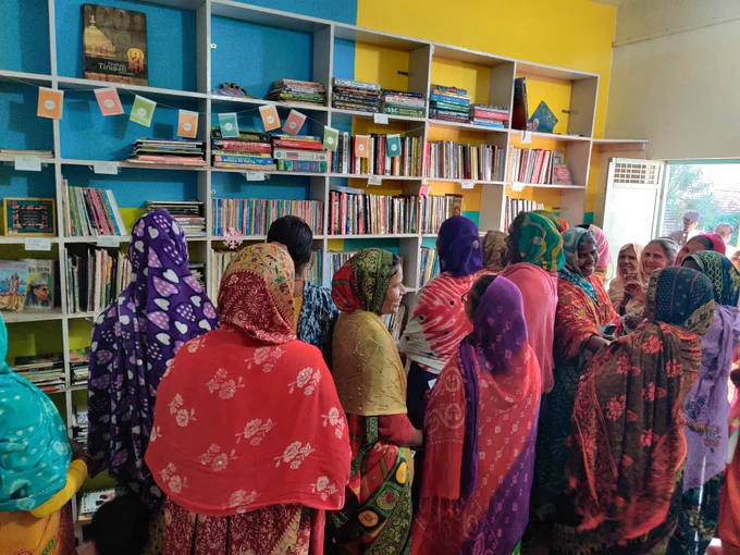 A group of women, many in colorful sarees, step inside the reading room of Bansa Community Library for the first time. Their expressions are a mix of awe and curiosity as they slowly move around the shelves, touching books with gentle wonder. Some are smiling, others silently observing the space. The atmosphere is warm and quiet, filled with the sound of footsteps and pages turning. These women walked 6.5 km from their village to visit the library after a community outreach walk.