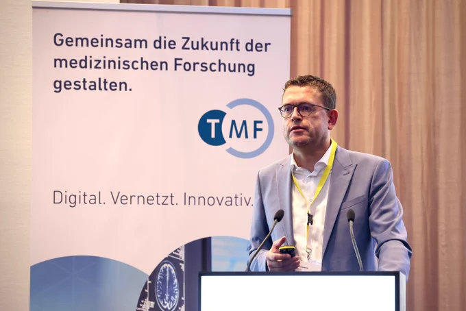Ein Mann steht am Rednerpult mit Mikrofonen.
