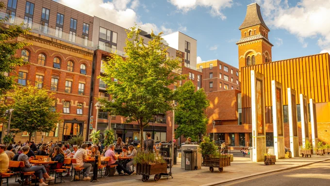 People sitting and chatting and enjoying the sunshine in the Cutting Room Square in Ancoats.