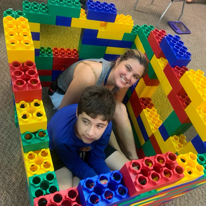 students participating in activities in the classroom including building blocks, foam, and coloring