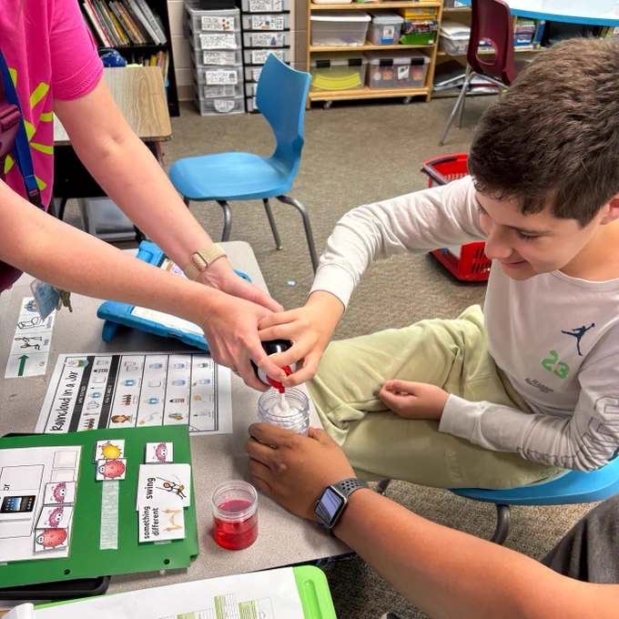 students participating in activities in the classroom including building blocks, foam, and coloring