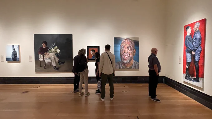 View of portraits near the entrance into the Portrait Award Exhibition at the National Portrait Gallery - including the large portrait by Tim Benson which won the Second Prize. 