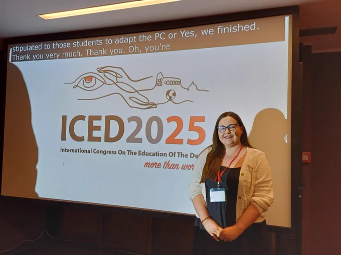 Caroline standing beside a screen with the ICED1025 logo. 