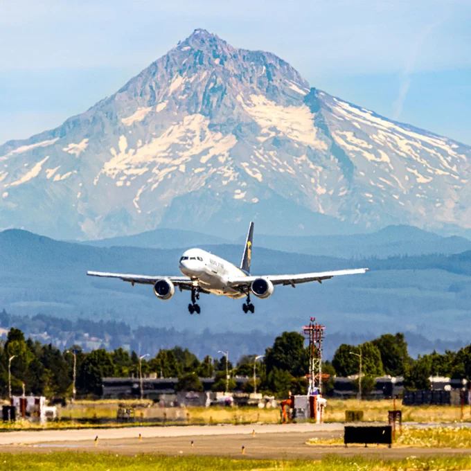 A UPS plane landing in front of snow-covered mountains.
