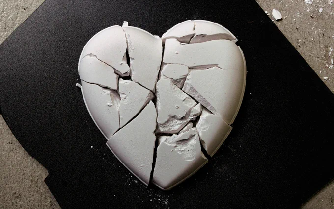 Photo of a white ceramic heart, shattered.
