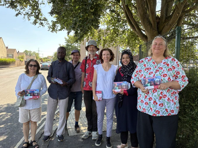 Anneliese stood on a pavement with Oxford Labour councillors and campaigners, with some holding leaflets, all in the sunshine.