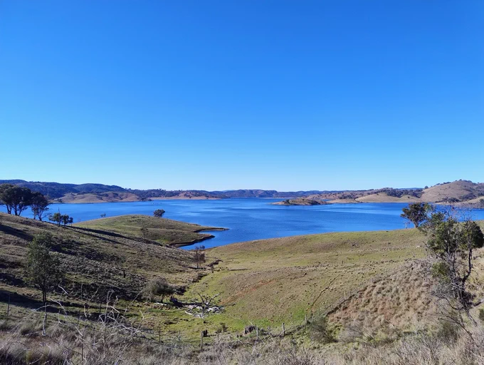 Looking across green farmland toward Windemere Dam near Mudgee. 
There is not a cloud in the bright blue sky and the water is even bluer.