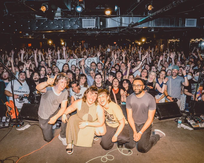 photo of Bad Moves on stage with the audience waving their hands in the background