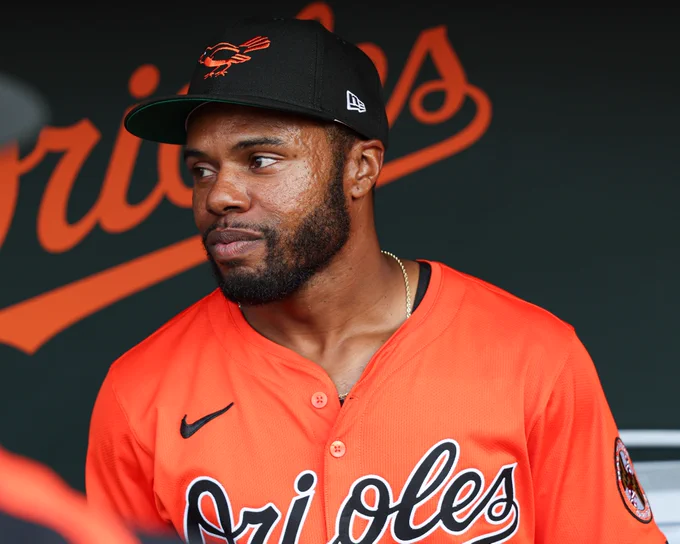Cedric Mullins in the Orioles dugout before tonight's game. He is wearing an all orange Orioles uniform and Hall of Fame Weekend Orioles cap.