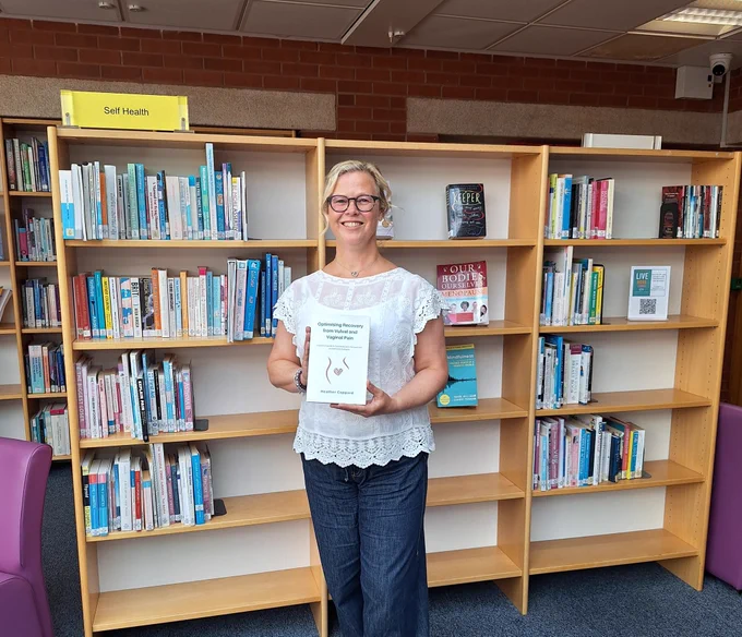 A photo of the author holding the book in the library.