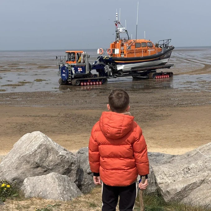 A young supporter stood on a path watching a Shannon with the Shannon Launch and Recovery System on the beach. 