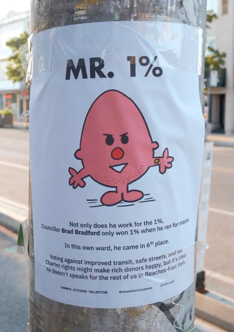 A poster on a pole outside of Councillor Brad Bradford's rarely open constituency office. It's an image of a pink, egg shaped Roger Hargreaves Mr Men-style character with the tile "Mr. 1%". Underneath it reads: 

"Not only does he work for the 1%, 
Councillor Brad Bradford only won 1% when he ran for mayor. 

In this own ward, he came in 6th place.

Voting against improved transit, safe streets, and our 
Charter rights might make rich donors happy, but it's clear 
he doesn't speaks for the rest of us in Beaches-East York."