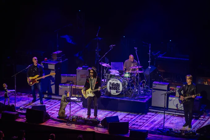 Wide shot of Mike Campbell & The Dirty Knobs singing and playing instruments on the Ryman stage