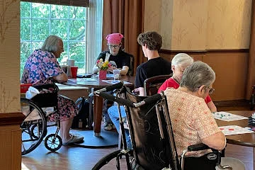 students engaging with elderly by playing bingo at local nursing home