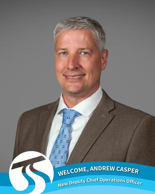 Portrait of Andrew Casper, Spokane Transit’s new Deputy Chief Operations Officer. He’s wearing a brown suit jacket, white shirt, and blue patterned tie, smiling in front of a gray background. A Spokane Transit logo and welcome banner at the bottom reads: “Welcome, Andrew Casper – New Deputy Chief Operations Officer.”