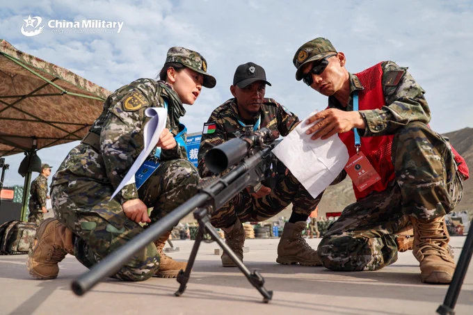 Photo shows a Chinese armed police soldier briefing a Madagascan contestant on the weapon specifications during the Sharp Blade 2025 International Sniper Competition on the afternoon of July 15, 2025.