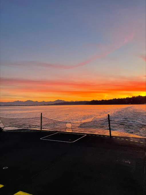 View off the back of a ferry of an orange sunset.