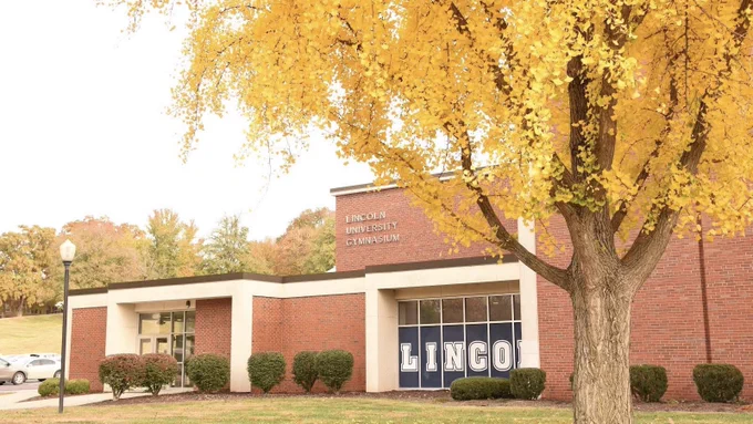 Exterior image of Jason Gymnasium on the Lincoln University of Missouri campus, with the word “Lincoln” visible in the window and framed by yellow fall leaves.