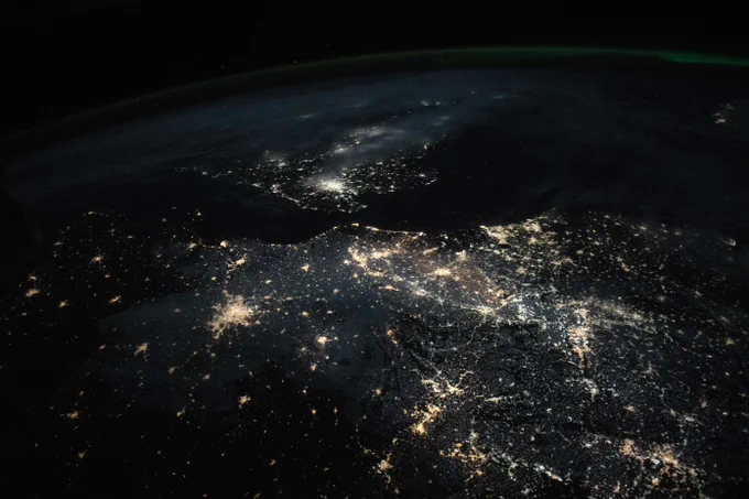 A satellite image of northwestern Europe at night shows several urban centers that appear as bright clusters of light.