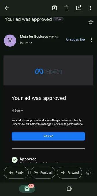 This is a screenshot of an email notification from Meta for Business with the subject line "Your ad was approved." The email is displayed in a dark-themed mobile email interface.

The email shows:
- Sender: Meta for Business (with a purple "M" avatar)
- Time: 9:37 AM
- Subject: "Your ad was approved" (also shown in the inbox preview)
- The Meta logo prominently displayed in the email body

The email content reads:
"Hi Danny,

Your ad was approved and should begin delivering shortly. Click 'View ad' below to manage it or view its performance."

There's a blue "View ad" button below the message text.

At the bottom, there's a green checkmark icon with "Approved" status text.

The email interface shows typical mobile email options including Reply, Reply all, Forward buttons, and an unread message indicator showing "99 " in the bottom left corner.