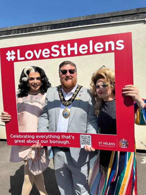 Mayor of St Helens Borough, Cllr Seve Gomez-Aspron, pictured with two drag queens holding #LoveStHelens photoboard at St Helens Pride