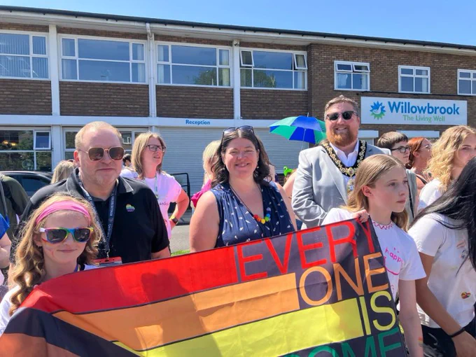 Mayor of St Helens Borough, Cllr Seve Gomez-Aspron, pictured with St Helens Borough Council Deputy Leader Cllr Bond and Merseyside Police and Crime Commissioner Emily Spurrell with group at St Helens Pride holding flag.