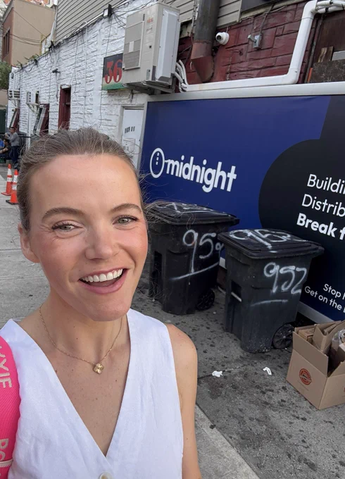 woman smiling in front of a billboard that say Midnight