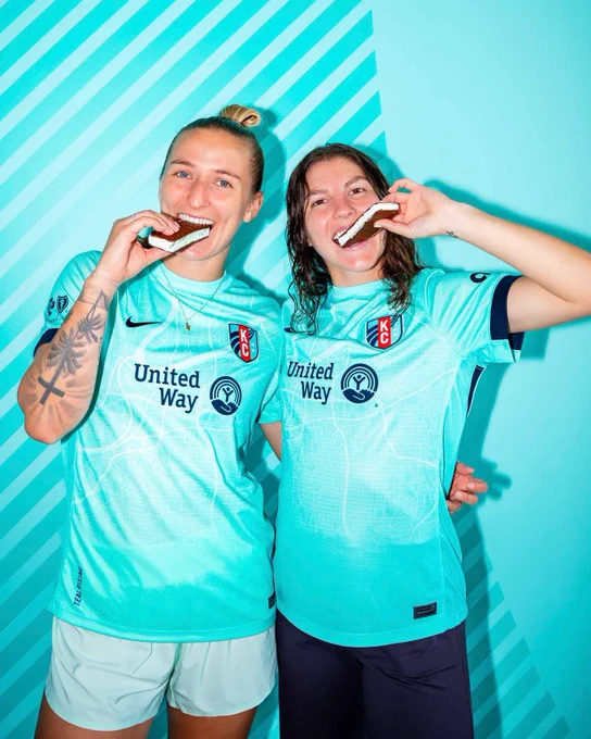 Players Hailie Mace and Izzy Rodriguez smiling holding ice cream sandwiches. 