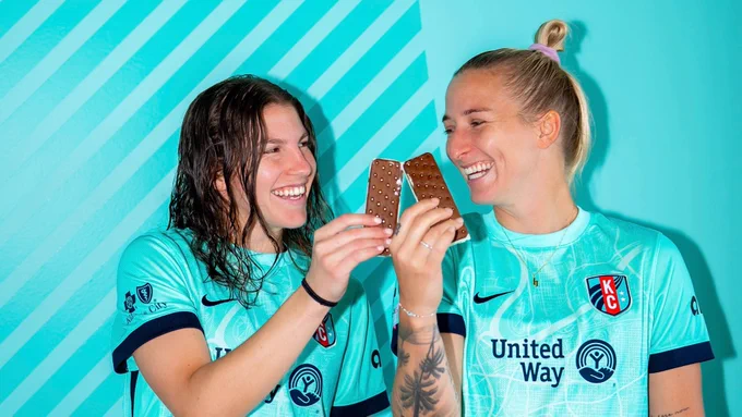 Players Hailie Mace and Izzy Rodriguez smiling holding ice cream sandwiches. 