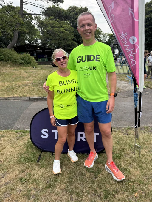 Kelly and Mike at the end of parkrun smiling and wearing hi-vis blind and guide tops