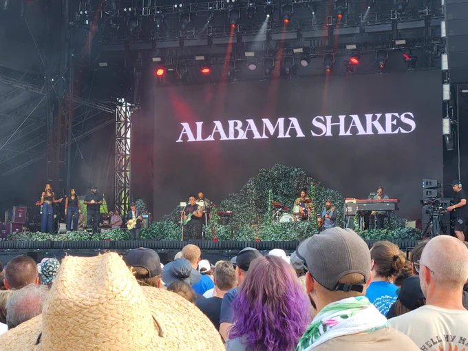 Alabama Shakes stage features greenery and a basic background with their name displayed. 