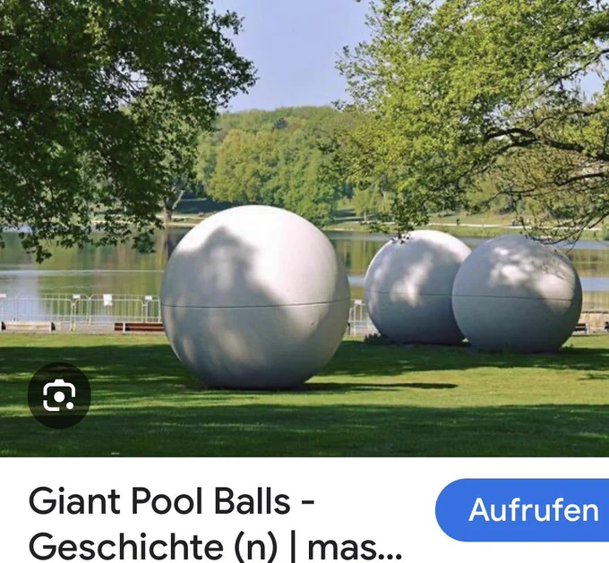 3 große Kugeln aus Beton auf einer Wiese an einem kleinen See