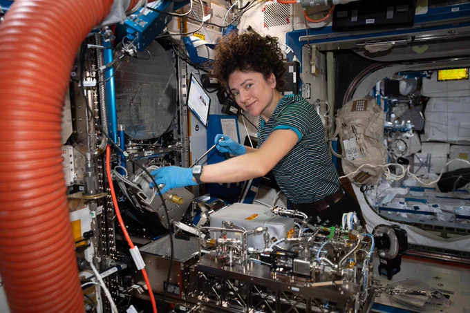 NASA astronaut Jessica Meir works on orbital plumbing tasks inside the Tranquility module's Life Support Rack. She is looking at the camera. A tablet floats in front of her. Credit: NASA/Jessica Meir