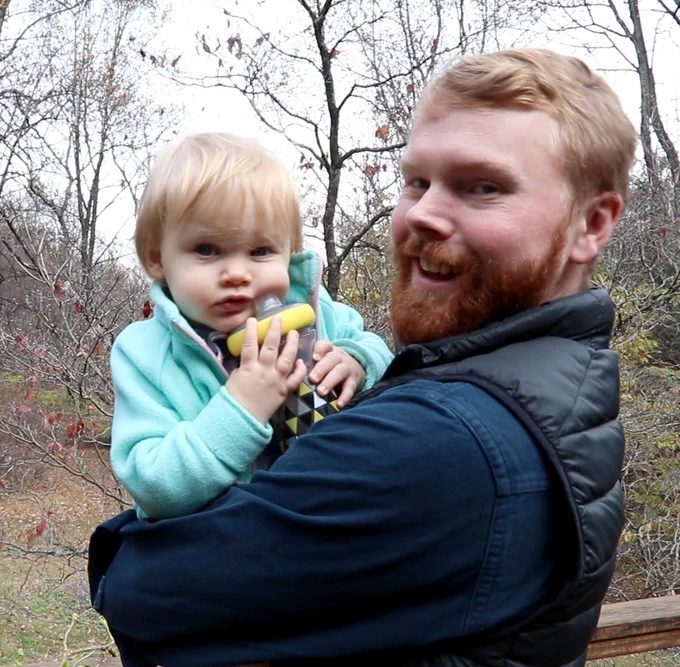Young man holding a small child in the woods. 