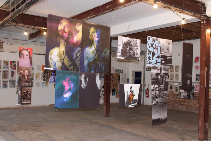 Art exhibition featuring lots of work hanging from ceilings and on the walls