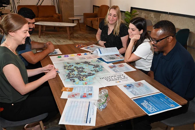 Five individuals are engaging in a board game at a table.