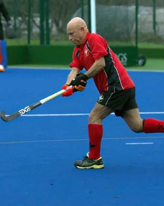 David playing hockey. He's wearing a red and nav blue sports kit.