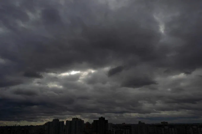 A heavily overcast sky casts a deep shadow onto the land beneath.