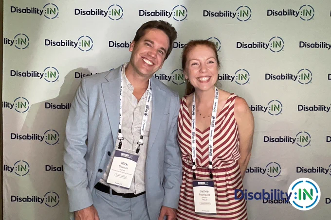 A male and female smiling, standing side-by-side. 