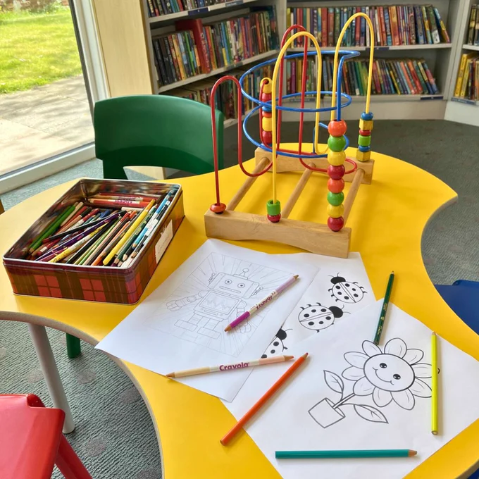 Photo of a table at Ash Library with colouring pages and colouring pencils. 