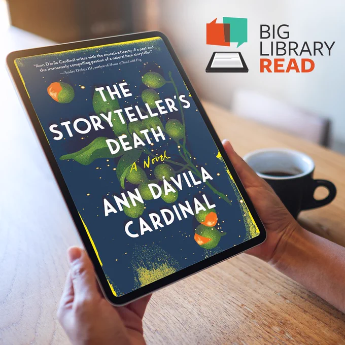 A person holds a tablet displaying the cover of the novel The Storyteller’s Death by Ann Dávila Cardinal. The cover features green fruit on dark leafy branches against a deep blue background with scattered golden dots. The book title is in large white letters. In the top right corner, the Big Library Read logo is visible, showing two overlapping speech bubbles and an open book icon. A black coffee cup sits on the wooden table in the background.