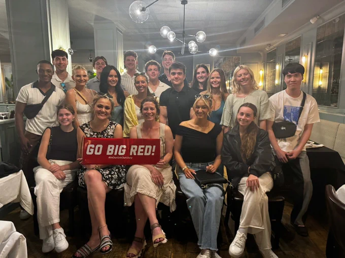 Fernand and other Huskers studying in Barcelona smile for a photo as they hold a sign that says "Go Big Red"